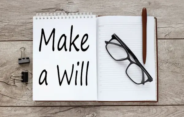 Wire bound notebook with the words Make a Will written on the front with a pair of spectacles and a pen  sitting on top reminding the user about making a Will