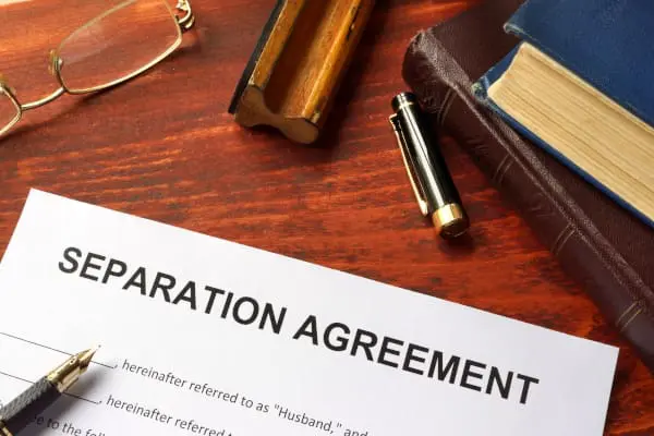 Separation Agreement sitting on a desk surrounded by a pair of spectacles, a stamp, a pen top and two text books on top of one another