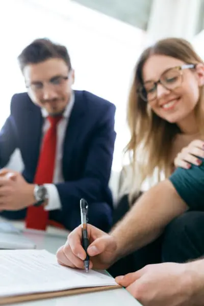 Couple making a Will with their solicitor in the background.