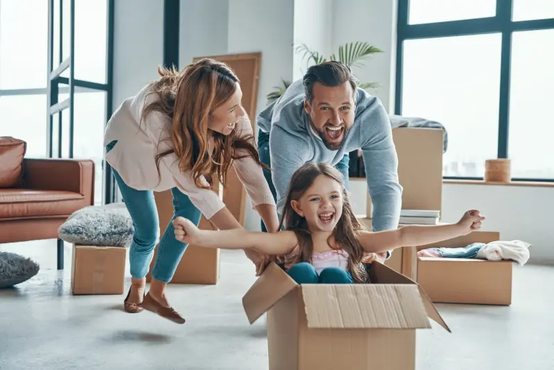 Couple celebrating moving into their house with their child after following Morgans Complete Guide to Buying a House in Scotland